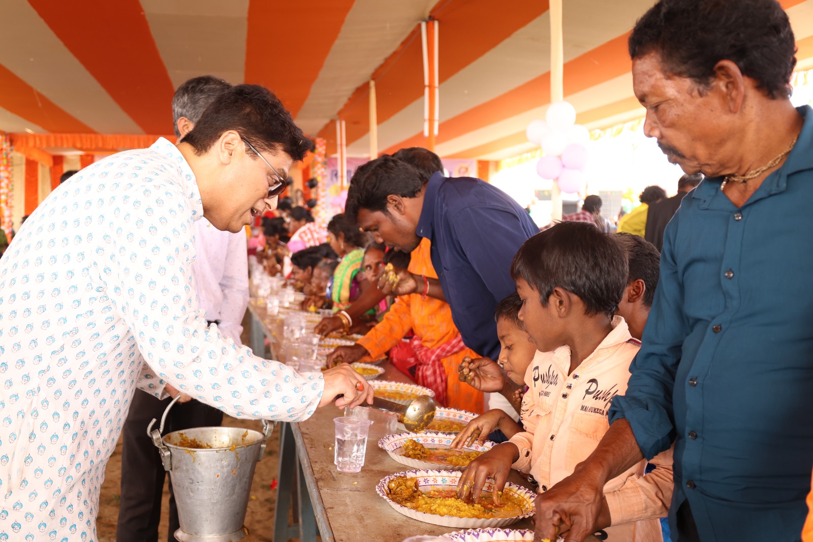 Volunteers serving a shared meal to children and elders